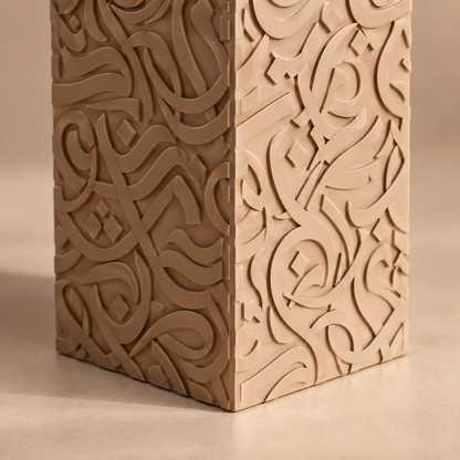 Close-up of raised Arabic calligraphy texture on the corner of a Dune and Bone matte vase