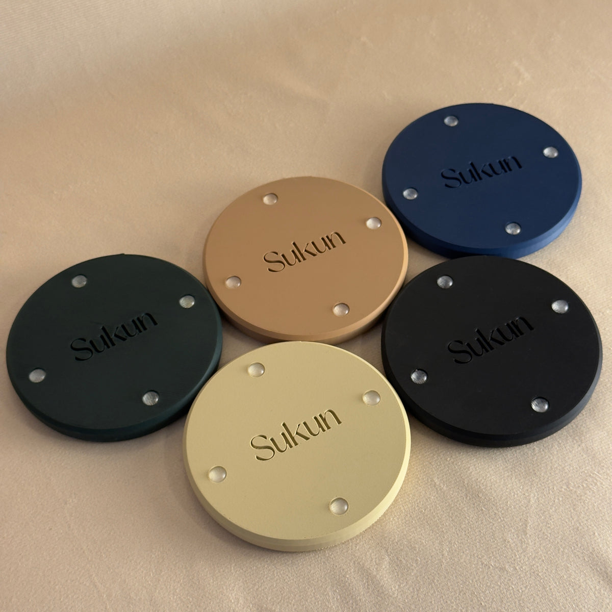 Underside of Arabic calligraphy coasters showing Sukun branding and non-slip pads in all five colourways